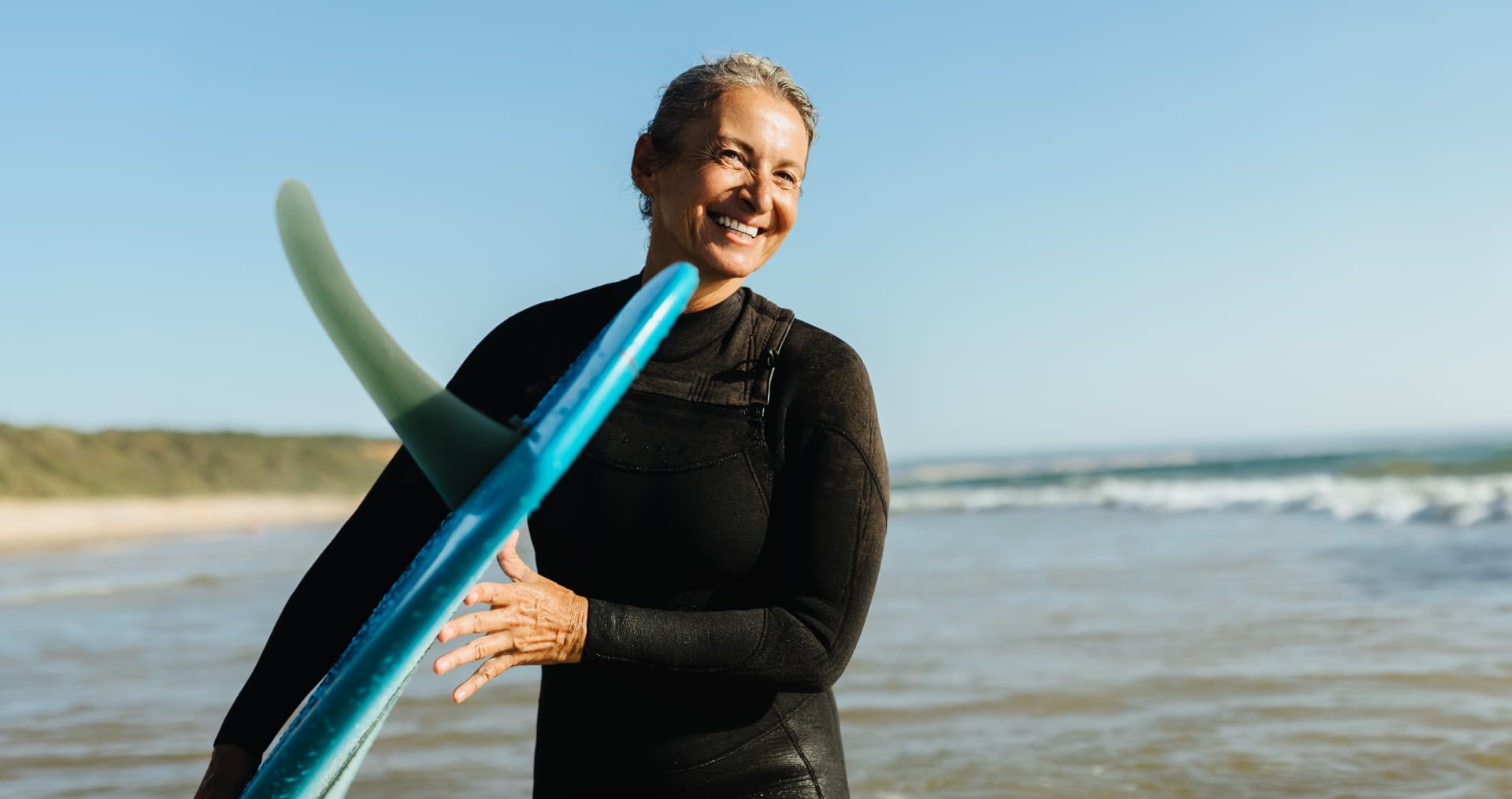 Mujer sonriente con una tabla de surf en la playa